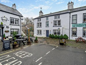 Un pub traditionnel avec une terrasse et une enseigne annonçant un plat du jour, à savoir un rôti.