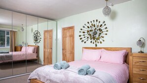 Un dormitorio con cama, cómoda de madera, espejo y un adorno en la pared.