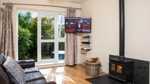 Una sala de estar con sofá, chimenea, televisión y vistas al exterior.
