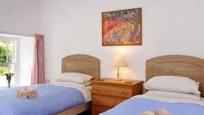 Ein Hotelzimmer mit zwei Betten, einem Nachttisch mit Lampe, einem Holz-Kopfteil und einem Bild an der Wand.