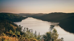 Ein ruhiger See, umgeben von Hügeln.