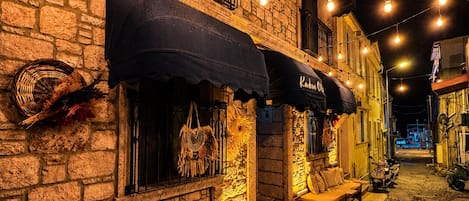 A cobblestone street with outdoor seating, stone buildings, and string lights.