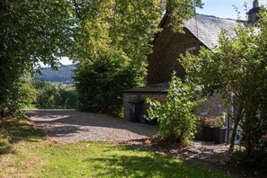 A stone building with a gravel driveway, surrounded by greenery and trees. - 3 Bed in Brecon (oc-bn427) (Llansantffraed)