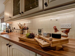 A kitchen with wooden countertops, a coffee maker, a toaster, and a decorative rooster. - 2 Bed in Llandovery (oc-bn426) (Llandovery)