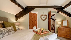 Ein Schlafzimmer mit einem Bett, einer Kommode, einer herzförmigen Dekoration und einem Tablett mit Frühstücksangeboten.