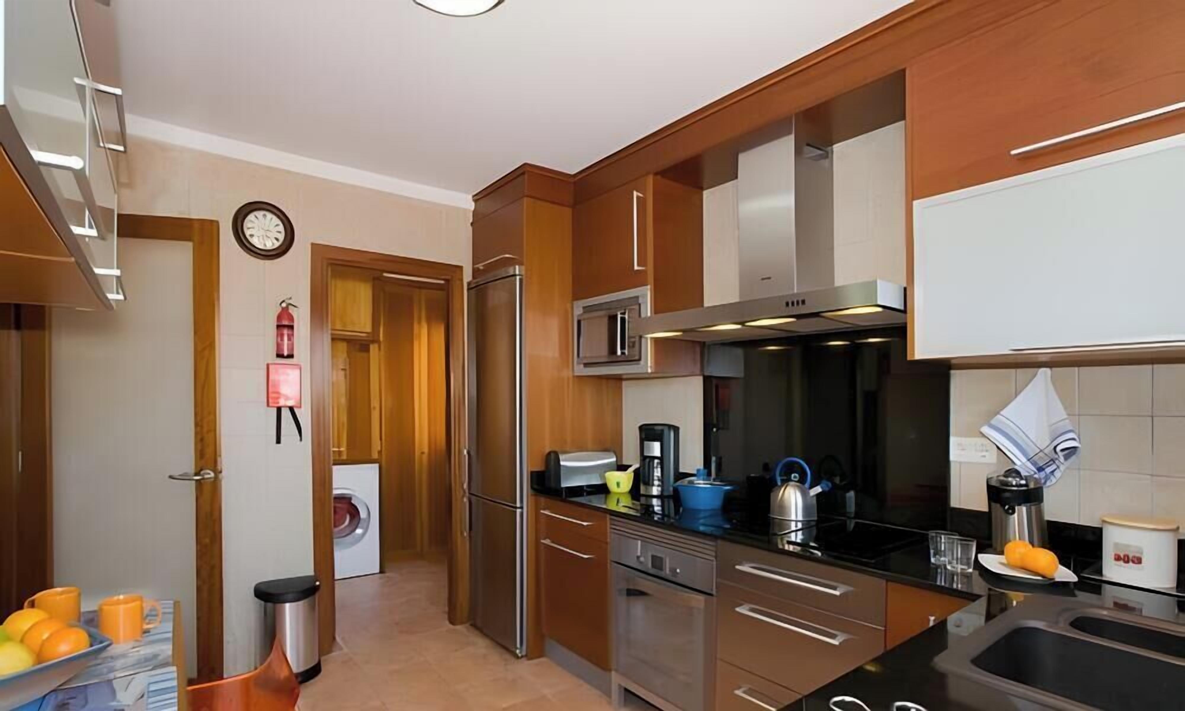 A modern kitchen with stainless steel appliances, wooden cabinets, and a built-in microwave.