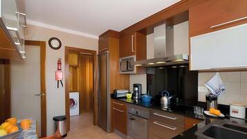 A modern kitchen with stainless steel appliances, wooden cabinets, and a built-in microwave.