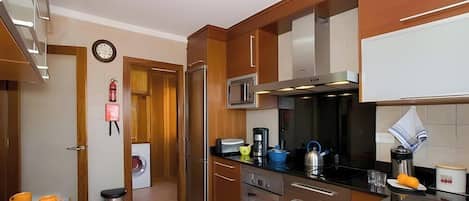 Une cuisine moderne dotée d’appareils électroménagers en acier inoxydable, de meubles en bois et d’un four à micro-ondes encastré.