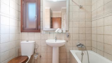 Een badkamer met toilet, wastafel en bad.