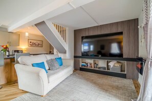 Ein modernes Wohnzimmer mit einer Couch, einem Flachbildfernseher und einer Treppe.
