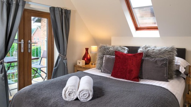 Ein Schlafzimmer mit einem Bett, einem Oberlicht, einem Nachttisch und einem Fenster mit Vorhängen.