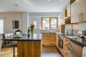 A modern kitchen with a central island, wooden cabinets, and stainless steel appliances.