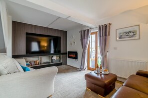 Ein Wohnzimmer mit Flachbildfernseher, Kamin, Sofa und Couchtisch.