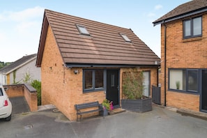 A residential property with a sloped roof, a front door, and a bench outside.