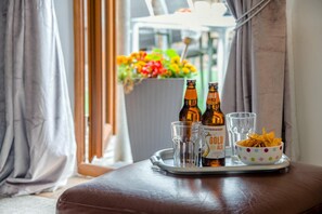 A tray with two bottles of Hatherwood Gold Ale, two glasses, and a bowl of chips on a brown leather ottoman. - 1 Bed in Builth Wells (oc-bn274) (Builth Wells)