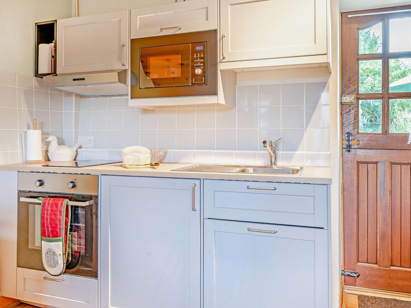 A kitchen with a microwave, oven, sink, and cabinets.