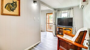 A room with a wooden TV stand, a framed picture on the wall, and a door leading to an outdoor area.