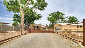 A fenced property with a gravel driveway leading to a building with a yellow exterior.