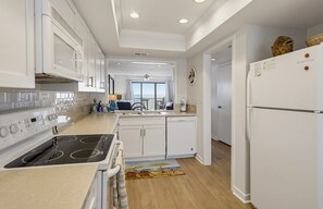 A modern kitchen with white cabinetry, a built-in stove, and a refrigerator. - 633 Newhaven  - Stunning Ocean Views (Fripp Island)