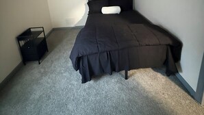 Ein Schlafzimmer mit einem Bett, einem kleinen Nachttisch, einer runden Leuchte und Wandbildern.