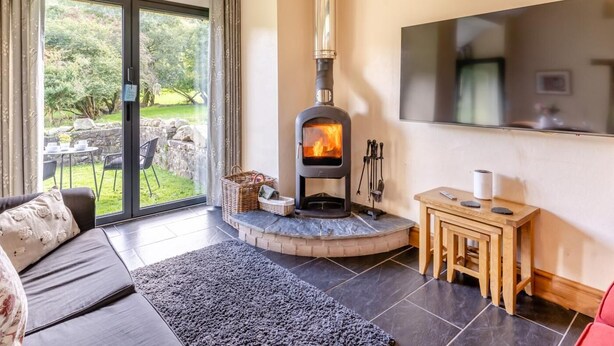 Ein gemütliches Wohnzimmer mit Kamin, einer Couch, einem kleinen Tisch und einem an der Wand befestigten Fernseher.