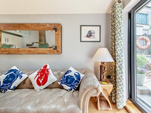 Um quarto com um sofá de couro, uma mesa de cabeceira de madeira com uma luminária, um quadro emoldurado e um espelho grande.