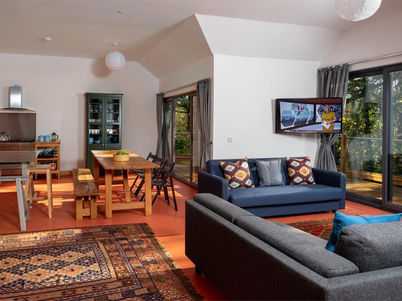 Ein modernes Wohnzimmer mit Sofa, Fernseher, Essbereich und Küche.