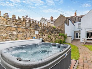 A stone wall, a hot tub, and a white building with a patio. - 4 Bed in Tenby (oc-fb193) (Tenby)