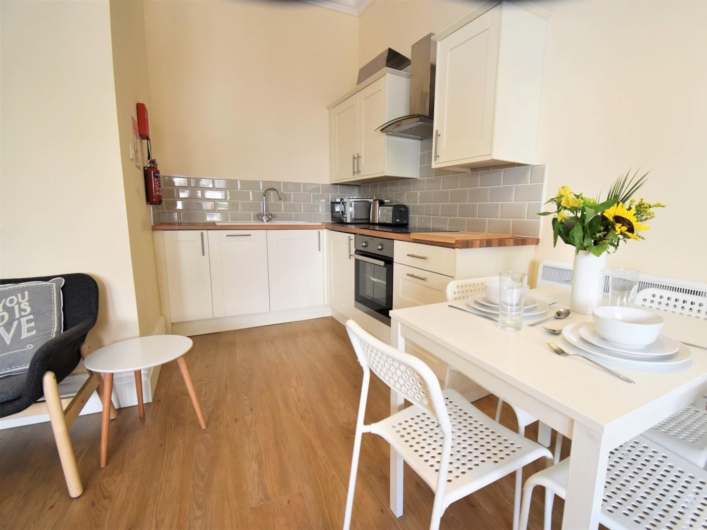 A modern kitchen with white cabinetry, a wooden countertop, and a dining area with a white table and chairs.