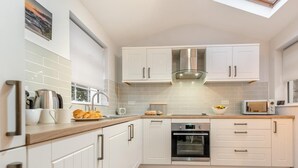 Een moderne keuken met witte kasten, een ingebouwde oven en een dakraam.
