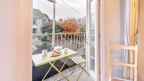 Een balkon met een tafel, stoelen en uitzicht op de straat.