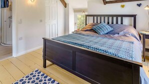 Ein Schlafzimmer mit einem Bett, einem Nachttisch, einer Wandleuchte und einem Fenster.
