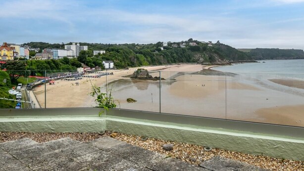 Un pueblo costero con una playa de arena, un promontorio rocoso y edificios a lo largo de la costa.
