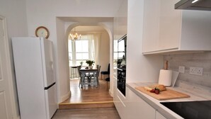 Una cocina moderna con armarios blancos, encimera de madera y estufa integrada.
