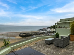Ein Küstenblick mit Strand, einer Pier und einem Gebäude mit einem Balkon mit Meerblick.