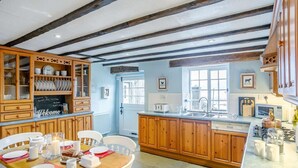 Una cucina con mobili in legno, un tavolo da pranzo per quattro persone e una finestra con vista.