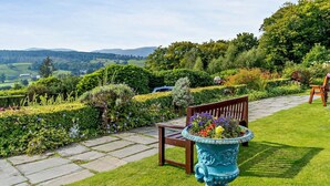 Ein Garten mit einer Bank, einer Zierurne und einem gepflasterten Weg.