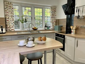 A modern kitchen with a wooden countertop, a sink, a stove, and a window with curtains. - 3 Bed in Ambleside (oc-81068) (Claife)