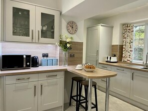 A modern kitchen with a microwave, toaster, and bar stools. - 3 Bed in Ambleside (oc-81068) (Claife)