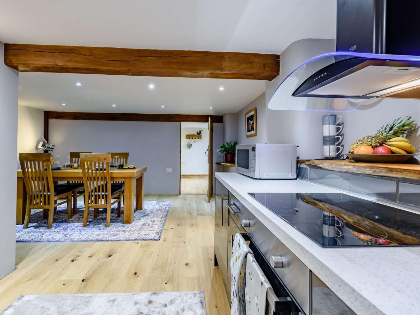 A modern kitchen with wooden beams, a dining area with a table and chairs, and a microwave on the counter.