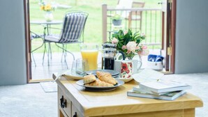 A breakfast setup with croissants, a coffee maker, a pitcher of orange juice, and a mug on a wooden table. - 2 Bed in Crediton (oc-81228) (East Worlington)