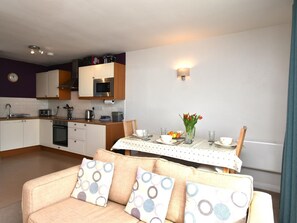 A compact living space with a kitchenette, dining area, and a sofa with patterned cushions. - 2 Bed in Saundersfoot (oc-fb293) (Saundersfoot)