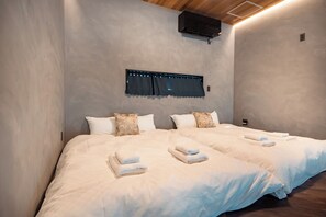 A double bed with white linens, two pillows, and a window with a curtain. - Private House Hibiki (Nara)
