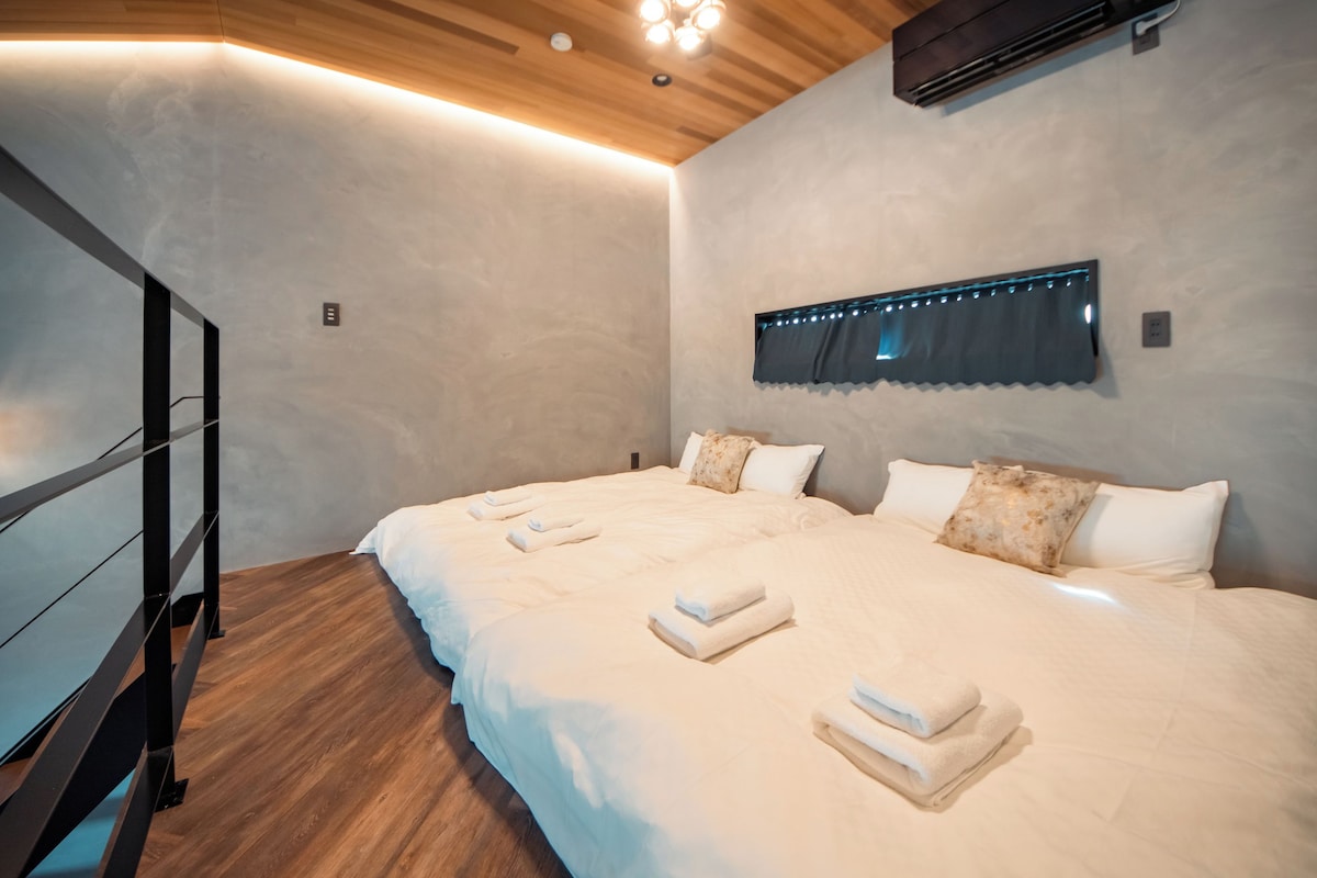 A bedroom with a large bed, a wooden ceiling, and a wall-mounted air conditioner.