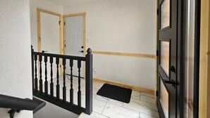A hallway with a black railing, a white door, and a wooden door frame.