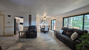 A modern living room with a sofa, armchair, and dining area.