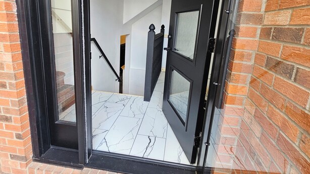 A doorway with a welcome mat, a clock, and a staircase leading inside.