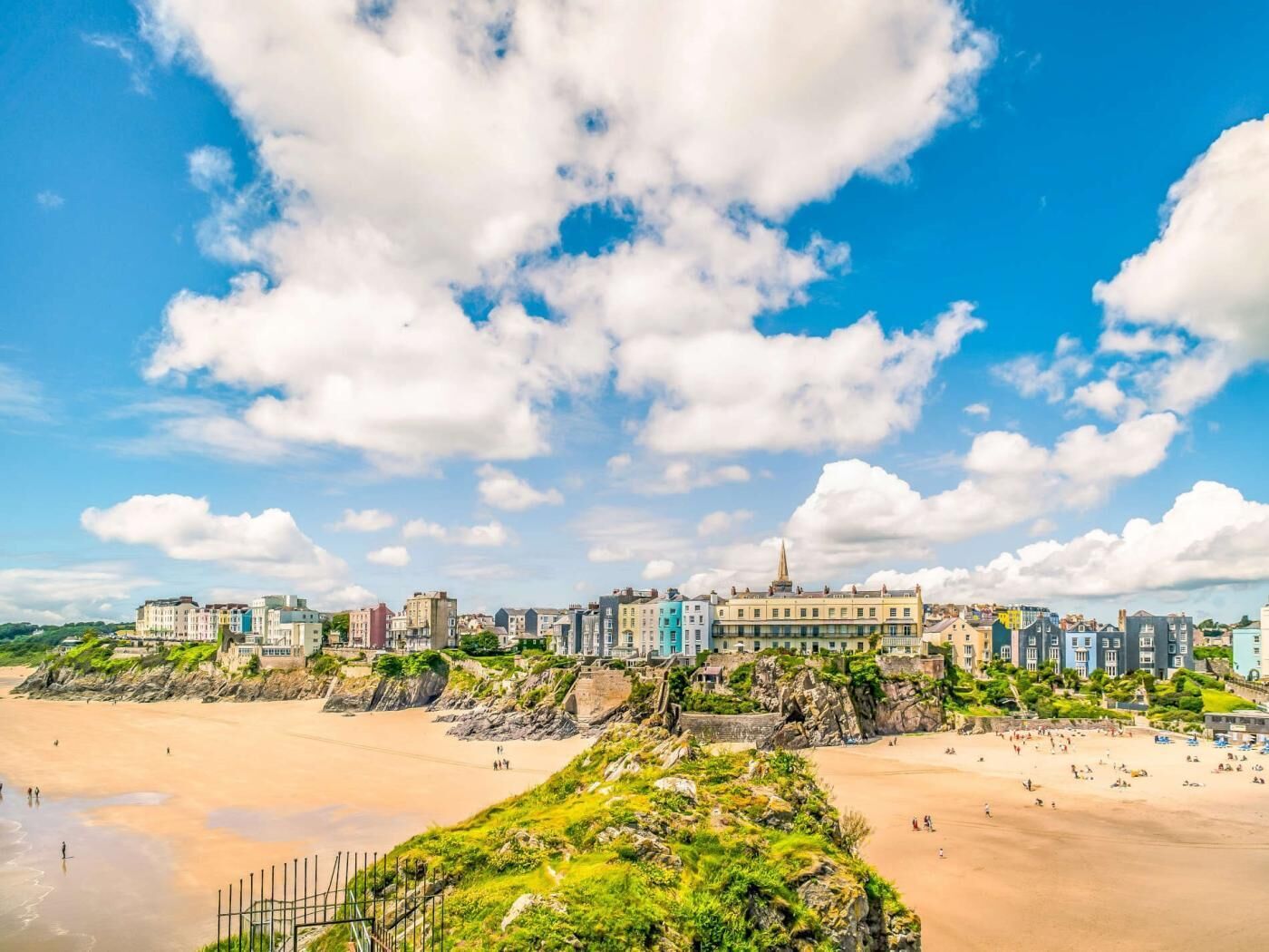 A coastal cityscape with buildings along the beach, a clear sky, and a sandy shore.