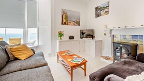 Ein Wohnzimmer mit einer Couch, einem Couchtisch, einem Kamin und Kunstwerken an den Wänden.