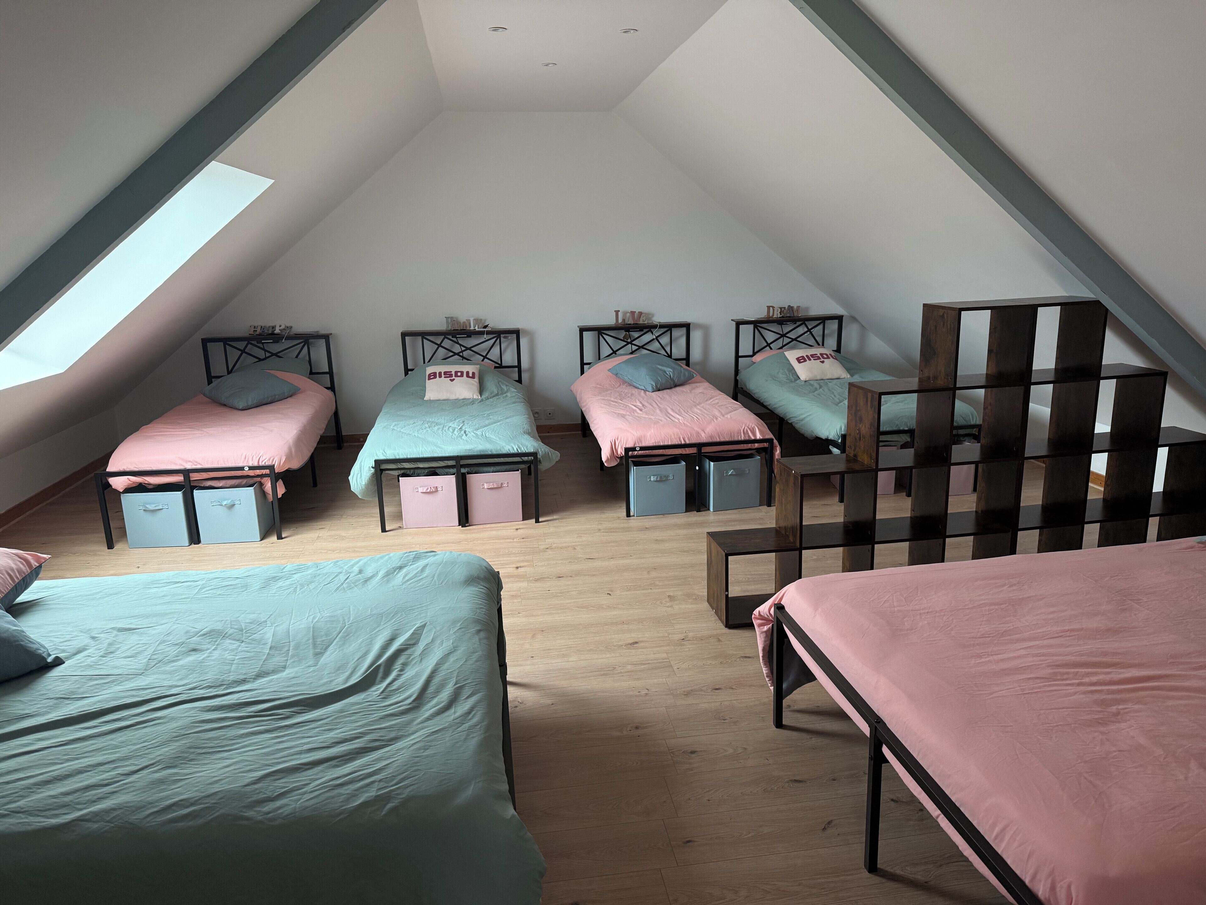 A dormitory room with four beds, each with storage drawers underneath, arranged in a row.